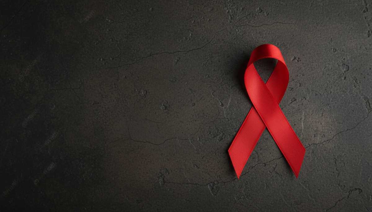 Red HIV awareness ribbon on dark background symbolising integrated HIV prevention and healthcare efforts in Kenya.