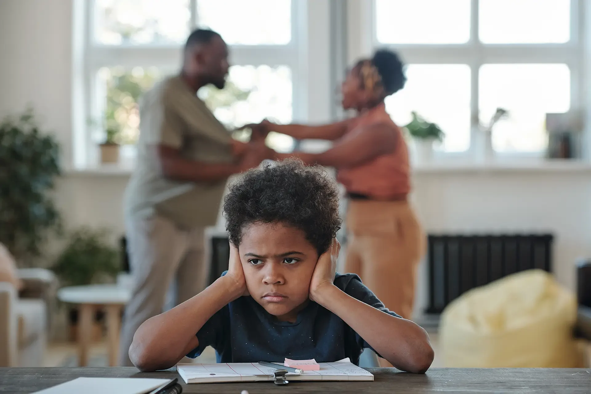 Child covering ears while parents argue in background