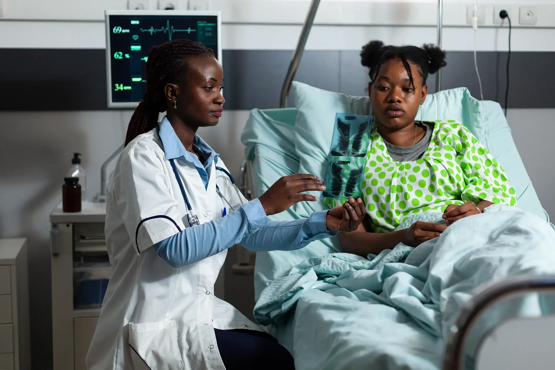 Female doctor showing chest X-ray to patient in hospital bed
